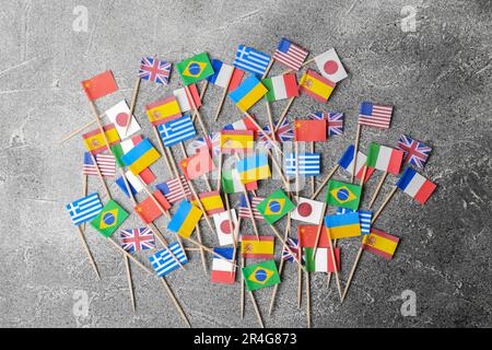 De nombreux petits drapeaux en papier de différents pays sur table grise, à plat Banque D'Images