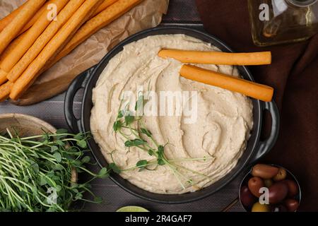 Délicieux houmous avec bâtonnets de grissini servis sur une table grise, pondre à plat Banque D'Images