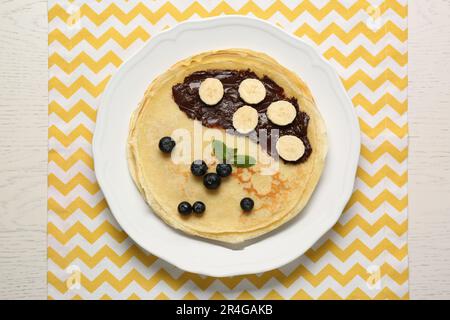 Pile de crêpes délicieuses avec baies fraîches, chocolat et banane sur table en bois blanc, vue du dessus Banque D'Images