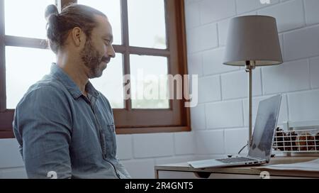 Un jeune homme s'inquiétait d'utiliser un ordinateur portable assis sur le bureau. Banque D'Images