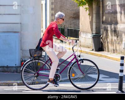 Femme vélo dans la rue de la ville - Tours, Indre-et-Loire (37), France. Banque D'Images