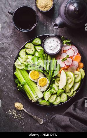 Salade saine avec des légumes frais et des œufs durs sur une assiette noire. Vue de dessus avec gros plan. Banque D'Images