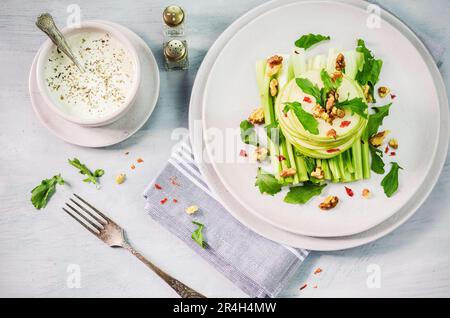 Salade Waldorf avec pommes vertes, céleri, cresson et noix grillées sur une assiette. Banque D'Images