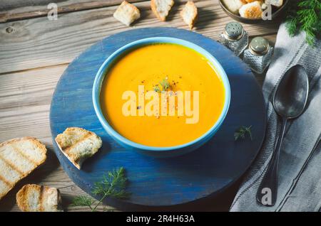 Soupe de pommes de citrouille rôtie servie avec du pain rôti et recouverte d'une saupoupe de poivre noir fraîchement moulu Banque D'Images