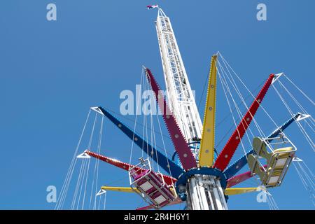 Manège à vide moderne, Wave Swinger ou Mega Whirlligig dans un parc d'attraction contre un ciel bleu. La partie supérieure rotative du carrousel s'incline également Banque D'Images