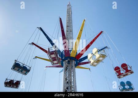 Manège à vide moderne, Wave Swinger ou Mega Whirlligig dans un parc d'attraction contre un ciel bleu. La partie supérieure rotative du carrousel s'incline également Banque D'Images