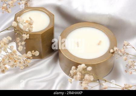 Bougies parfumées dans une casserole. Bougies de cire de soja sur fond de tissu blanc et de gypsophila Banque D'Images