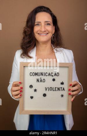 Une femme souriante qui donne un tableau d'affichage. Gestion démocratique et motivante. Isolé sur fond marron. Banque D'Images