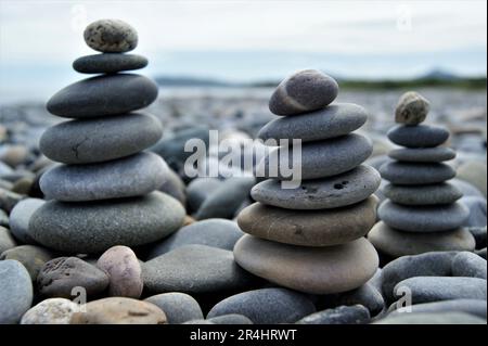 Trois tours Zen sur une plage de sable. Tours en galets. Banque D'Images