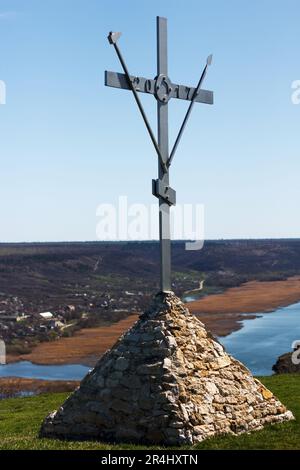 Croix de fer sur un piédestal en pierre contre fond de rivière Banque D'Images