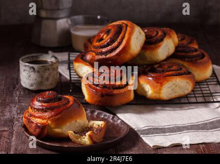 Levure de pâte de Cinnabons avec graines de pavot, raisins secs et fruits confits, servis avec du café. Style rustique. Banque D'Images