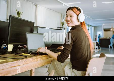 Portrait d'une femme souriante qui travaille sur un ordinateur portable dans un bureau créatif Banque D'Images