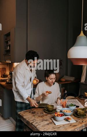 Couple reading newspaper pendant le petit-déjeuner à la maison Banque D'Images