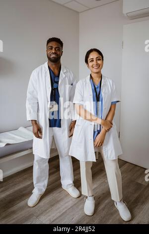 Des collègues médicaux souriants, hommes et femmes, debout dans la salle de consultation Banque D'Images