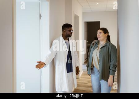Infirmière de sexe masculin aidant la patiente à entrer dans la salle de consultation de l'hôpital Banque D'Images