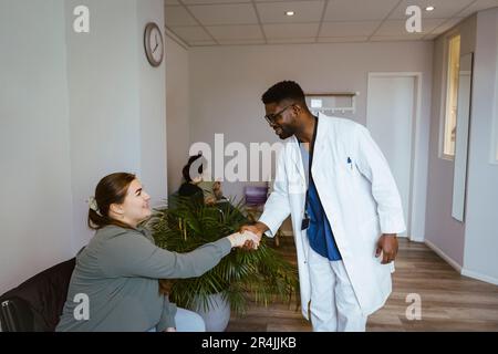 Souriant médecin saluant femme patiente assise dans la salle d'attente à la clinique Banque D'Images
