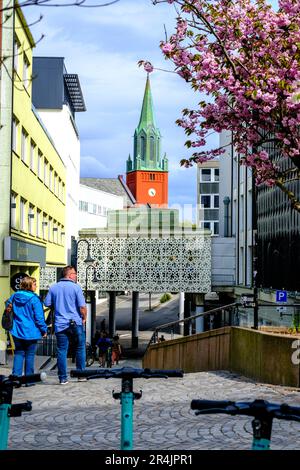 Stavanger, Rogaland, Norvège, 19 mai 2023, Homme et Femme, Couple de marche de la vieille ville Stavanger zone commerçante avec l'église historique Steeple dans le Backgroun Banque D'Images