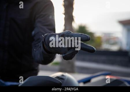 Gros plan des mains d'un cycliste montrant le geste de la main de salut, le geste V. Banque D'Images