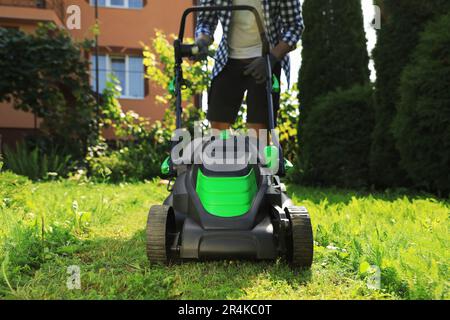 Homme qui allume la tondeuse dans le jardin, gros plan. Coupe de l'herbe Banque D'Images