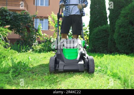 Homme qui allume la tondeuse dans le jardin, gros plan. Coupe de l'herbe Banque D'Images