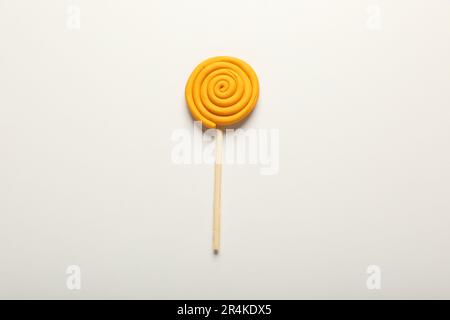Lollipop jaune fait de plasticine sur fond blanc, vue de dessus Banque D'Images
