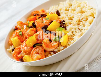 Crevettes grillées aux Caraïbes aux haricots noirs, salsa à la mangue et à l'ananas, servies avec du riz brun dans un bol blanc, gros plan Banque D'Images