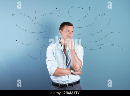 Choix dans la profession ou dans d'autres domaines de la vie, concept. Prise de décision, jeune homme réfléchi entouré de flèches dessinées sur fond de couleur Banque D'Images