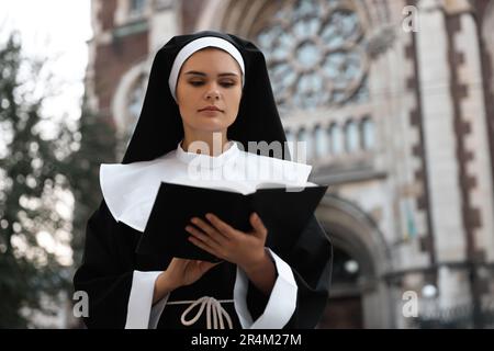 Jeune nonne lisant la Bible près de la cathédrale en plein air Banque D'Images
