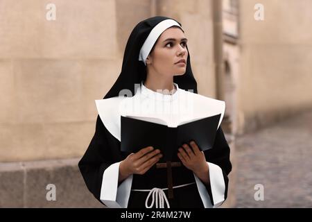Jeune nun lisant la Bible près de bâtiment à l'extérieur Banque D'Images