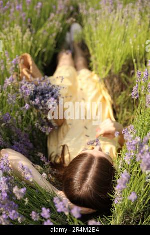 Jeune femme couché dans le champ de lavande le jour d'été Banque D'Images