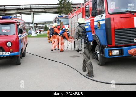 Un grand véhicule de secours incendie rouge, un camion pour éteindre un incendie et des pompiers sont prêts à travailler dans une raffinerie de pétrole, pétrochimie Banque D'Images