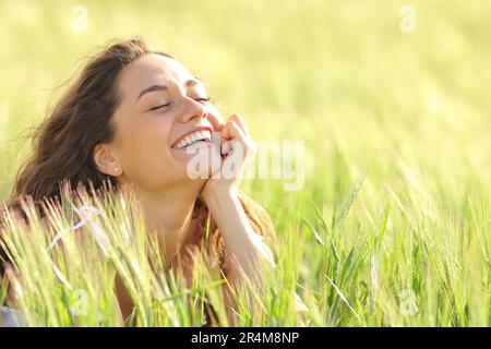 Drôle de femme appréciant de la nature riant dans un champ Banque D'Images