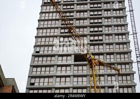 Grande grue industrielle de fret de construction puissante sur un site de construction de nouveaux bâtiments et maisons contre le ciel. Banque D'Images