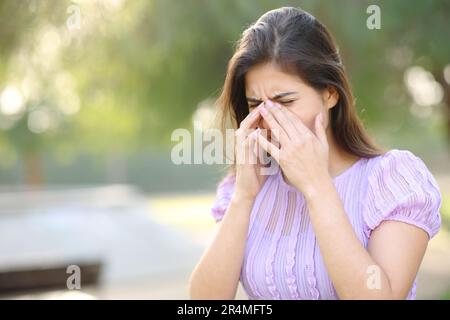 Femme allergique se grattant les yeux en été dans un parc Banque D'Images