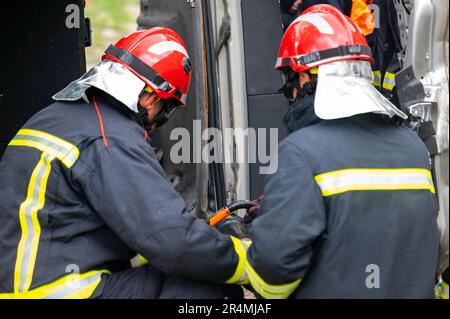 Pompiers utilisant des outils hydrauliques pendant une formation d'opération de sauvetage. Les secouristes déverrouillent le passager dans la voiture après un accident. Photographie de haute qualité. Banque D'Images