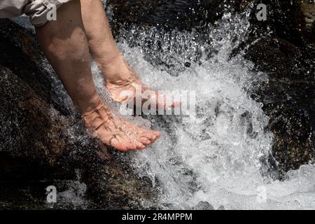 Detailed view of women cooling tired feet in a cold alpine river Banque D'Images