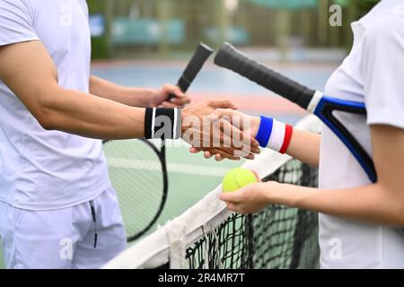 Des joueurs de tennis masculins et féminins se sont mis à serrer les mains sur le filet sur le court de tennis après le match. Bonne esprit sportif, l'amitié gagne Banque D'Images