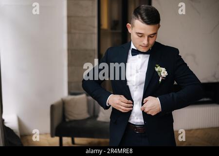 Portrait de beau marié en costume bleu foncé se préparant pour la première vue avec la mariée. Jour de mariage Banque D'Images