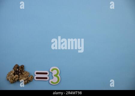 Trois noyaux de noyer placés sur le bord d'un fond bleu, photographiés d'en haut. Banque D'Images