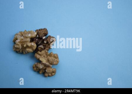 Trois noyaux de noyer placés sur le bord d'un fond bleu, photographiés d'en haut. Banque D'Images