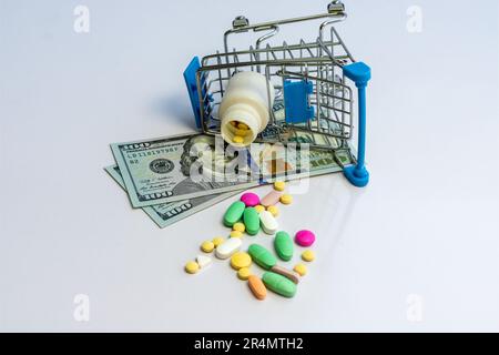 Divers comprimés et comprimés avec un chariot de shopping et des billets en dollars américains sur fond blanc isolé. Concept d'achat de médicaments. Banque D'Images