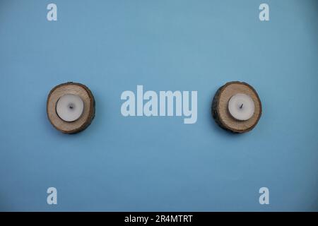 Petites bûches rondes et bougies avec un espace entre elles, photographiées d'en haut, placées sur un fond bleu Banque D'Images