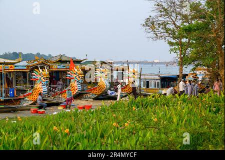 Plusieurs bateaux-dragons amarrés sur la rivière des parfums et des gens de la région qui vivent au quotidien sur la rive de Hue, au Vietnam. Banque D'Images