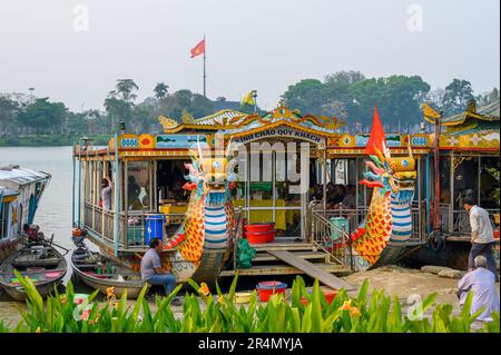 Des bateaux-dragons amarrés sur la rivière des parfums et un peuple local qui s'en va à la vie quotidienne sur la rive de Hue, au Vietnam. Banque D'Images