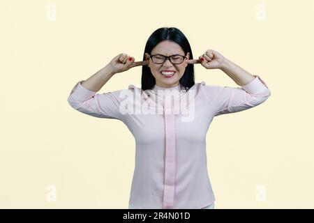 Portrait d'une jeune femme asiatique mettant les doigts dans ses deux oreilles. Isolé sur fond blanc. Banque D'Images