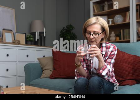 Pensive femme d'âge moyen pensive regardant loin s'asseoir seul à la maison se sentir anxieux solitaire, triste déprimé mélancholique vieille femme mature souffrent de douleur Banque D'Images