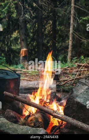 Feu de camp. Un chou-fleur de nourriture se trouve à proximité avec une hache en arrière-plan. Banque D'Images