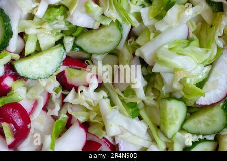 Mélange de salade de légumes. Salade végétarienne de radis, concombres, chou, sel, huile d'olive. Une alimentation saine. La salade de légumes mûrs hachés est mélangée Banque D'Images