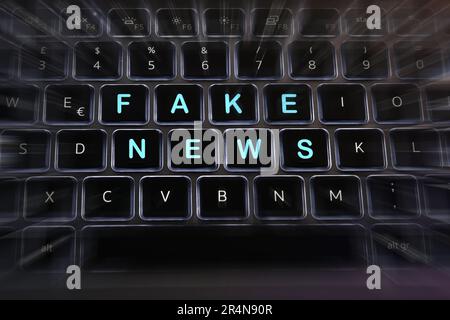 Fausses nouvelles écrites sur les touches d'un clavier d'ordinateur portable rétroéclairé avec effets de flou. Banque D'Images