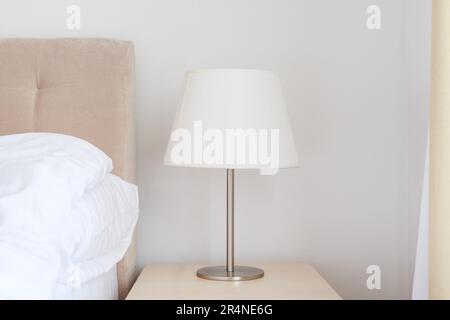 Lampe de chevet élégante avec abat-jour blanc sur table de nuit dans la chambre, mise au point sélective Banque D'Images